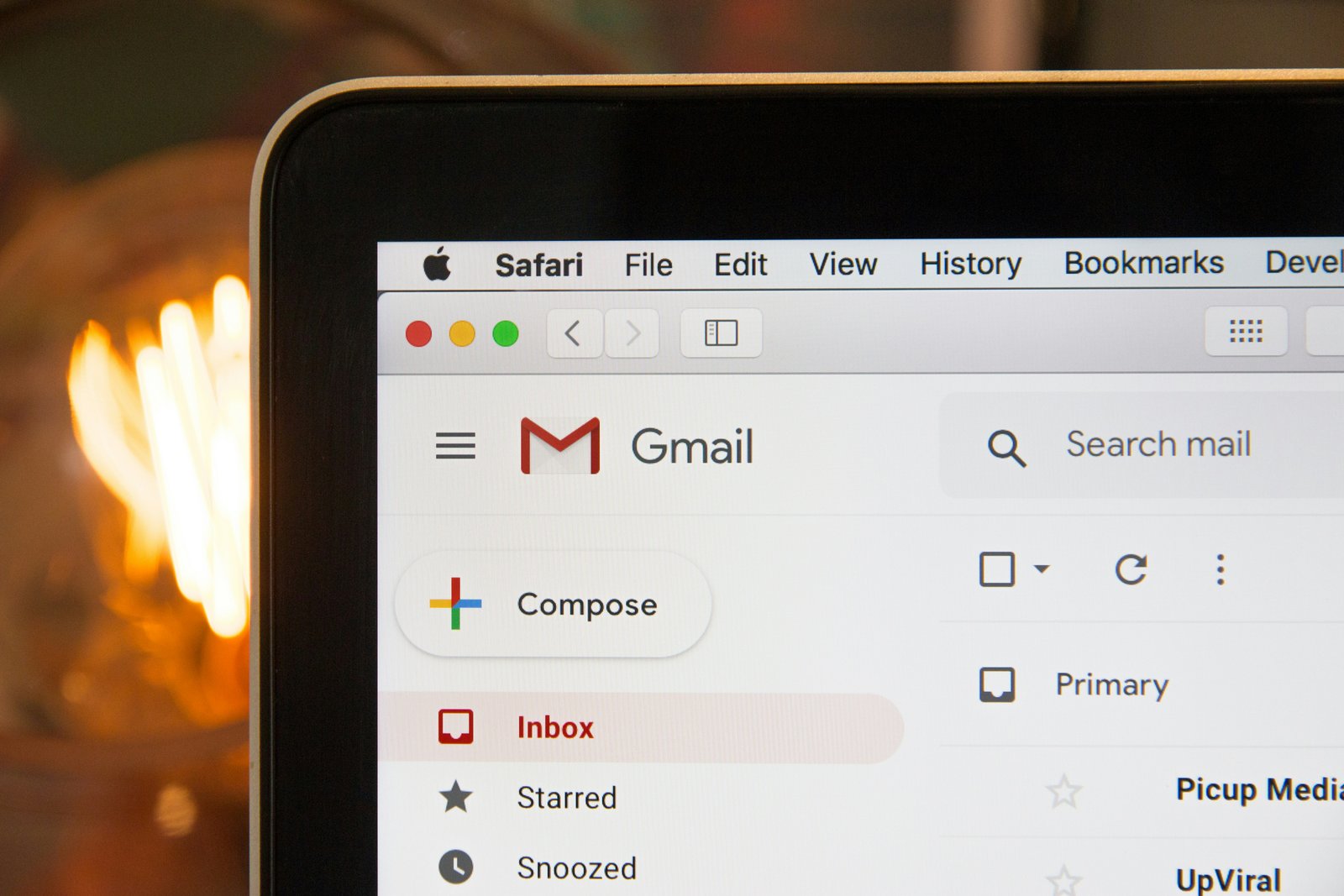 A laptop screen showing an email inbox with the compose button in view.