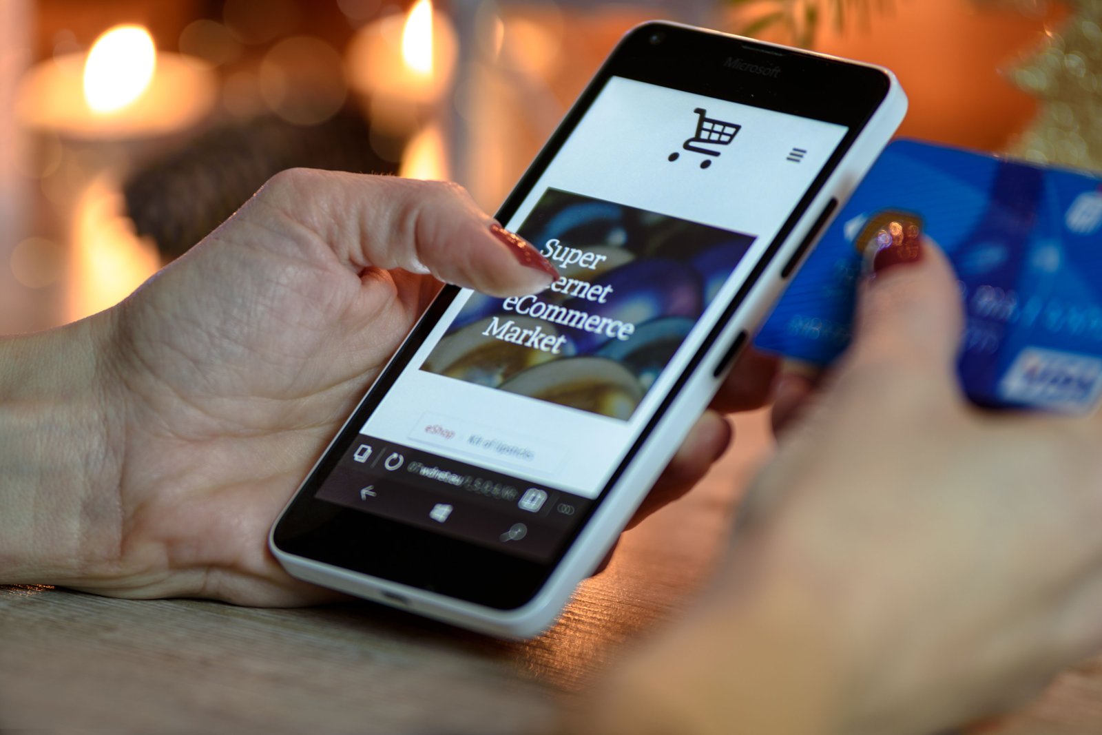 Someone holding a phone showing an online shop while holding a payment card.