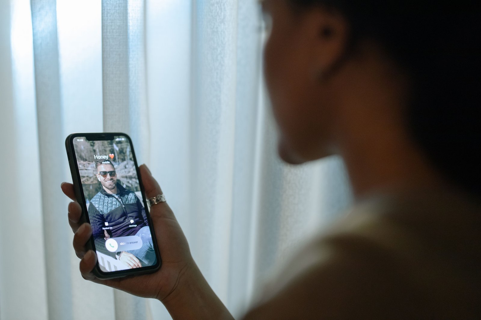 Someone holding a phone showing an incoming call from a contact saved as “Honey”.